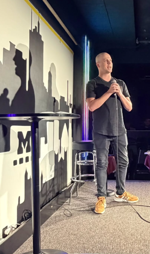 Jason Howell performing stand-up comedy on stage.